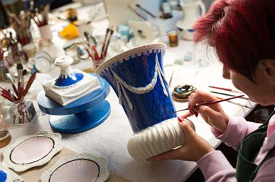 Художница посуды Cattin Porcellane Darte расписывает вазу.